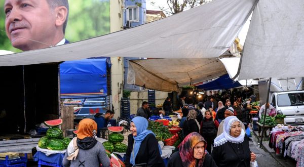 epa10610611 People shop at Kasimpasa neighborhood's local market with a picture of Turkish President Recep Tayyip Erdogan in the background, in Istanbul, Turkey, 05 May 2023. General elections will be held in Turkey on 14 May 2023 with a two-round voting to elect the President of Turkey and parliamentary elections held simultaneously to elect the members of the Grand National Assembly of Turkey.  EPA/SEDAT SUNA