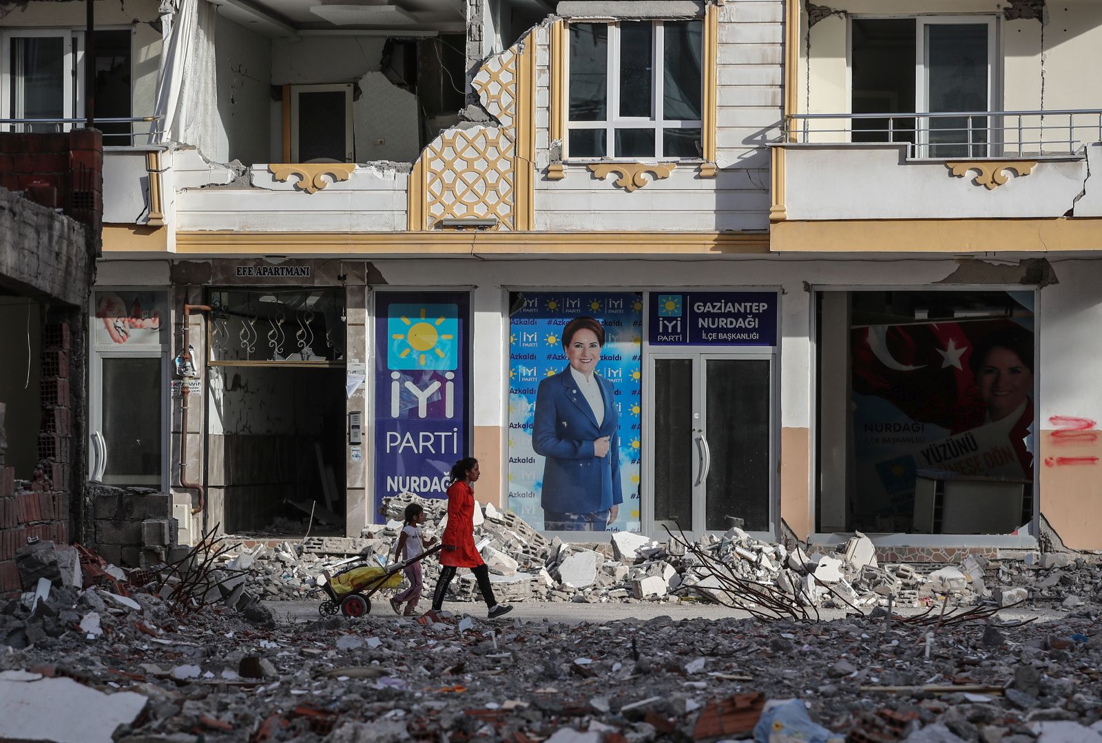 epa10610834 People walk in front of a picture of Turkish oppoisiton IYI Parti party leader Meral Aksener in Nurdagi district of Gaziantep, Turkey, 05 May 2023. More than 50,000 people died and thousands more were injured after major earthquakes struck southern Turkey and northern Syria on 06 February and again on 20 February 2023.  EPA/ERDEM SAHIN