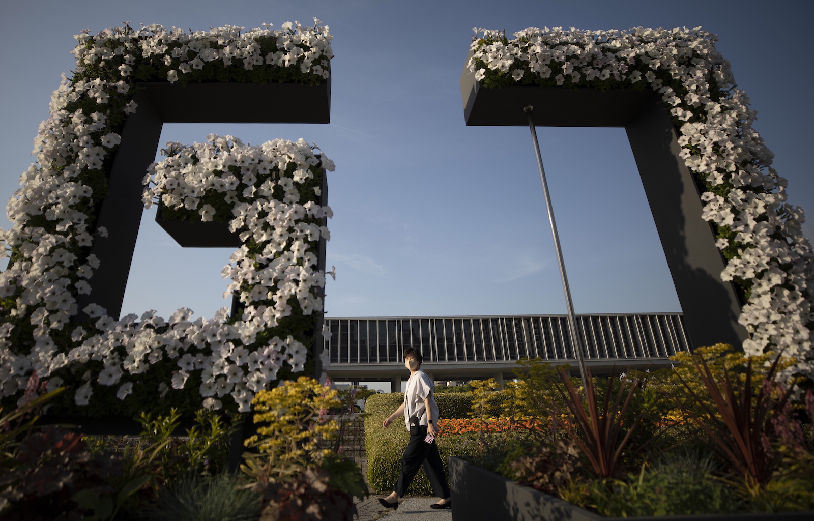 epa10633821 A woman walks past a G7 flower installation ahead of the G7 Summit at the Hiroshima Peace Memorial Park in Hiroshima, Japan, 17 May 2023. The G7 Hiroshima Summit will be held from 19 to 21 May 2023.  EPA/HOW HWEE YOUNG