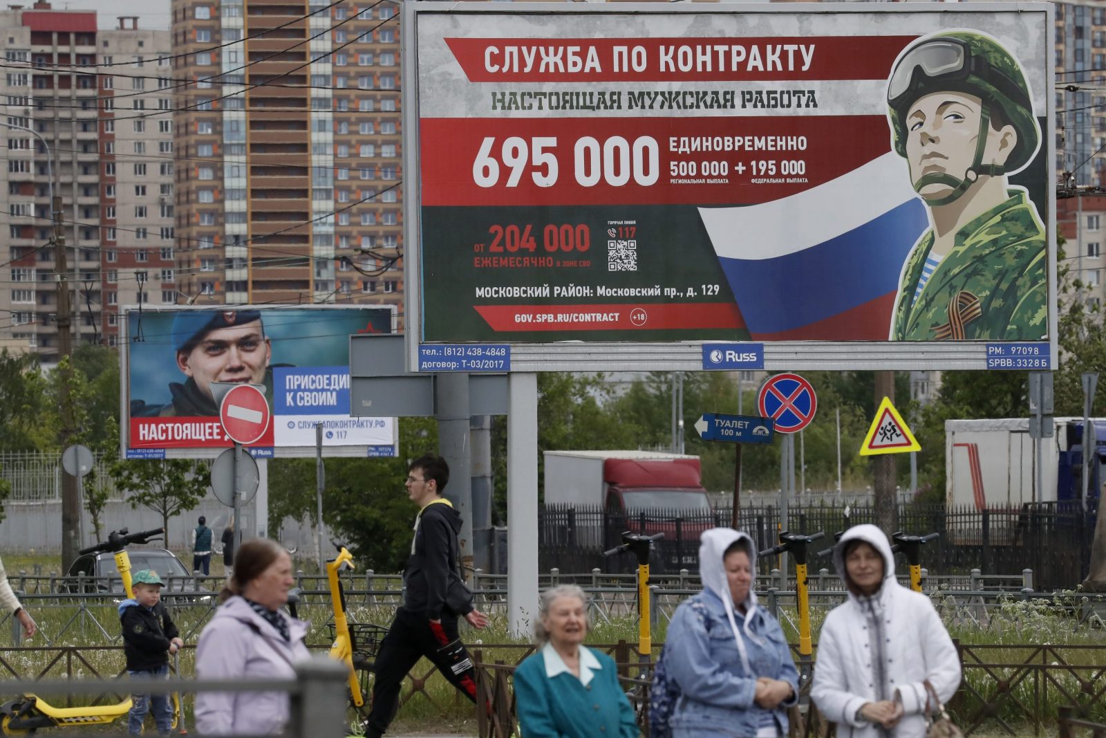 epa10662045 People walk past a billboard depicting a soldier, with a slogan reading 'Contract service. A real man's job' and 'Real deal. Join with your comrades', in St. Petersburg, Russia, 29 May 2023. On 24 February 2022, Russian troops entered Ukrainian territory in what the Russian president declared a 'Special Military Operation', starting an armed conflict.  EPA/ANATOLY MALTSEV