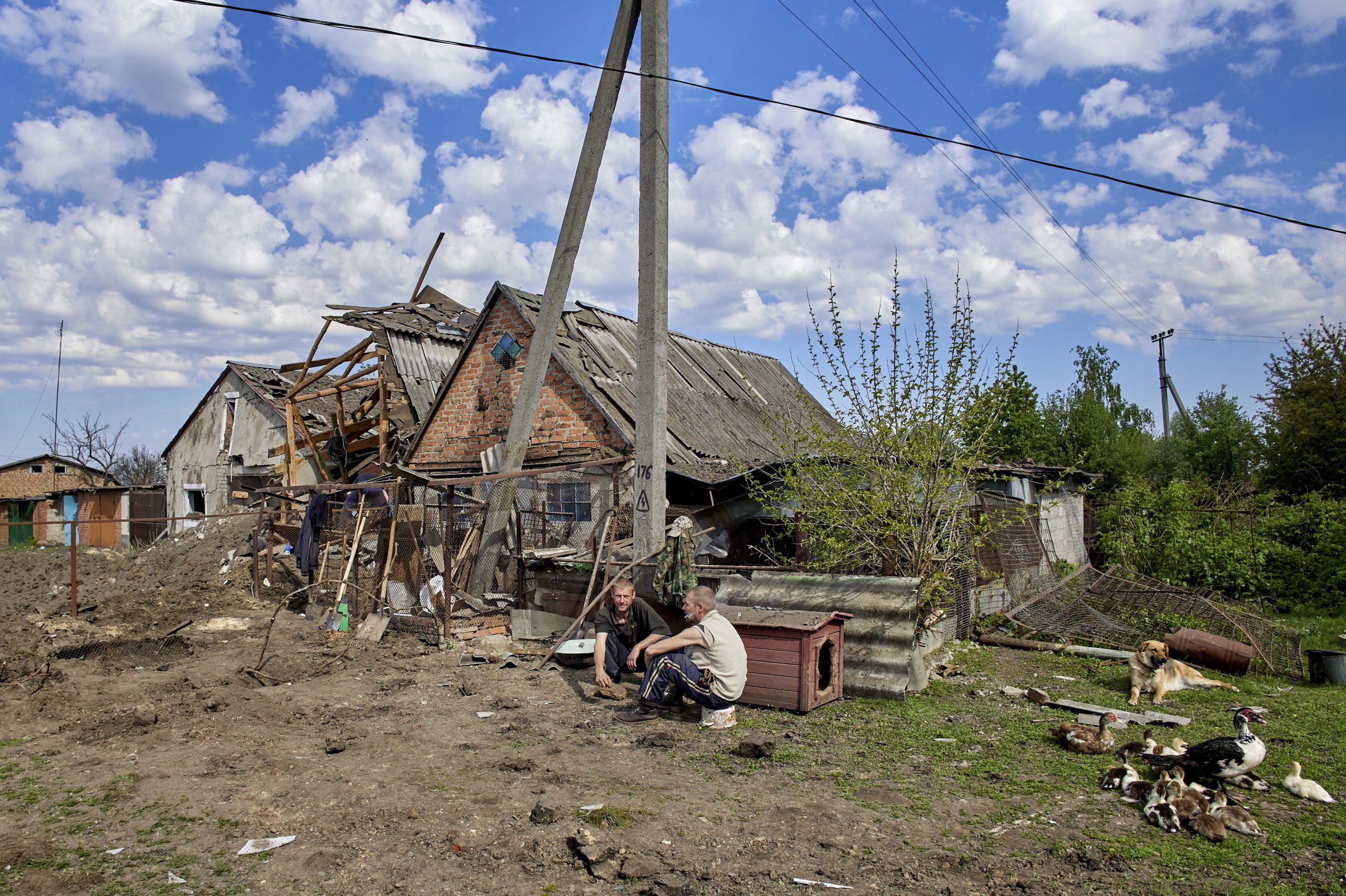 epa10627581 Locals sit next to a damaged building in the aftermath of a rocket attack in the Zolochiv settlement of the Kharkiv's area, Ukraine, 14 May 2023, amid the Russian invasion. Russian troops carried out S-300 missile strikes on Kharkiv and the Zolochiv settlement in the Kharkiv district on the night between 13 and 14 May. Some buildings and a transport infrastructure were damaged, the head of the Kharkiv Regional Civil-Military Administration Oleg Synegubov announced on 14 May. No victims were reported.  EPA/SERGEY KOZLOV
