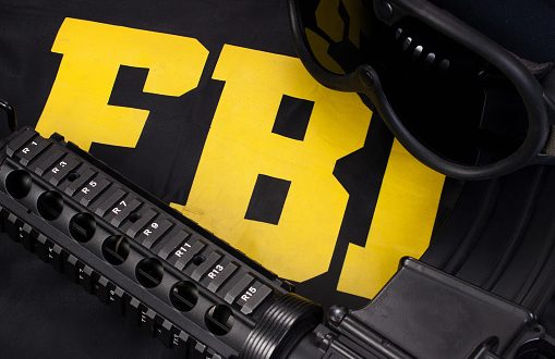 assault rifle and protective helm with goggles on fbi raid jacket black uniform background