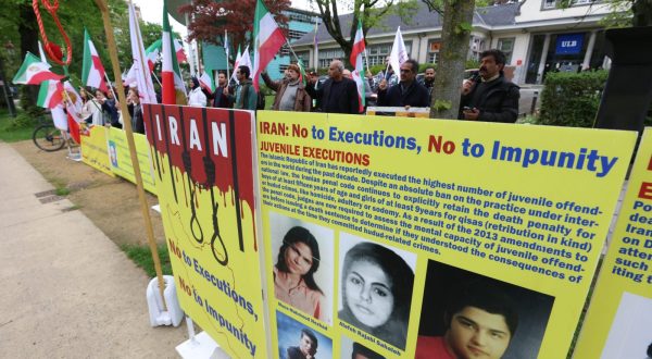epa10623181 Representatives of opposition group the National Council of Resistance of Iran (NCRI) stand near a placard against executions in Iran during a protest in front of Iranian embassy in Brussels, Belgium, 12 May 2023. According to the NCRI, the protesters are demanding the closure of the Iranian embassy.  EPA/OLIVIER HOSLET