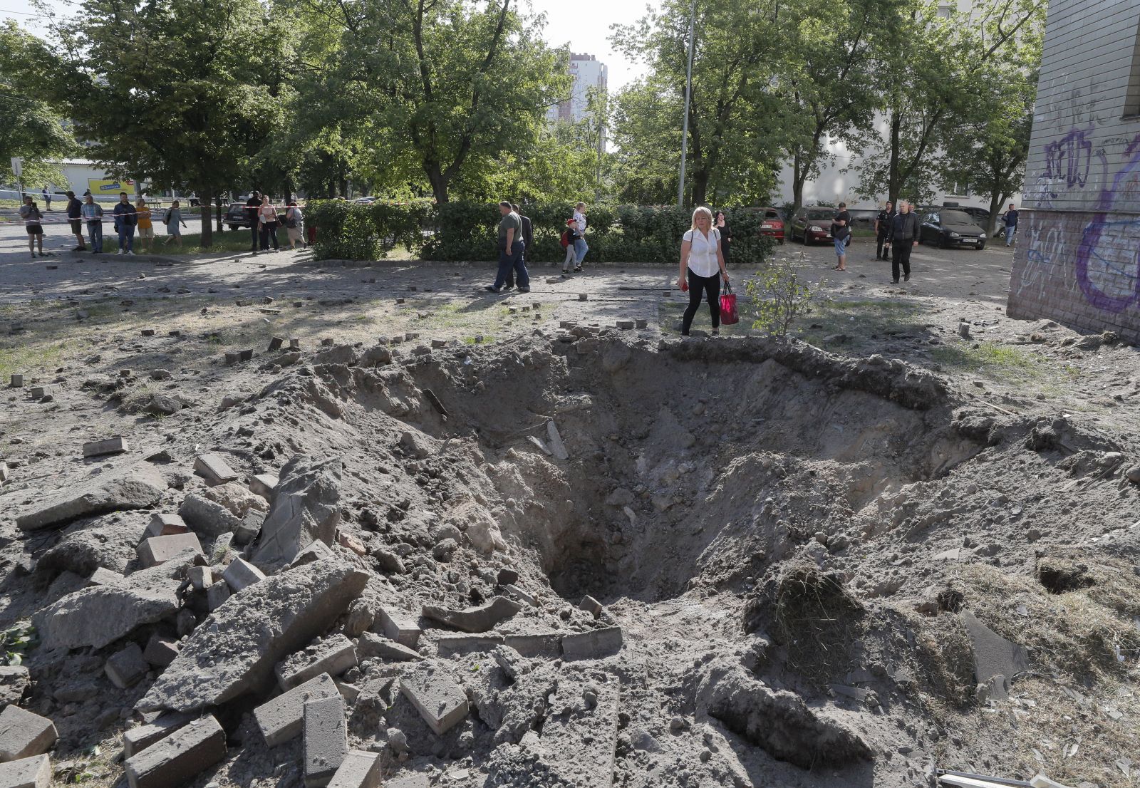 epa10666555 A person stands next to a shell crater near a residential building after a missile strike in Kyiv (Kiev), Ukraine, 01 June 2023, amid the Russian invasion. At least three people died, including a child, and ten others were injured after a missile attack on the Ukrainian capital, the National Police said. Russian troops entered Ukrainian territory in February 2022, starting a conflict that has provoked destruction and a humanitarian crisis.  EPA/SERGEY DOLZHENKO