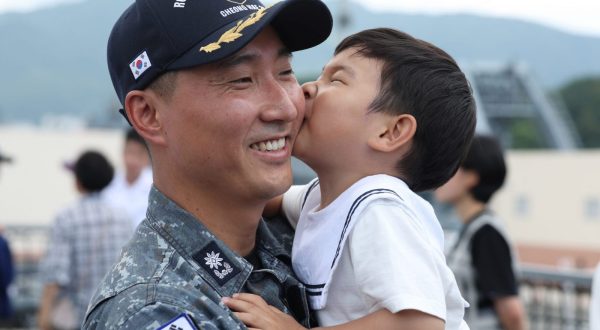 epa10704963 A naval officer is reunited with his son after returning from a six-month anti-piracy operation in waters off Somalia and the Strait of Hormuz during a ceremony to welcome the return of the 300-strong 38th contingent of the Cheonghae Unit at a naval base in Changwon, South Korea 22 June 2023.  EPA/YONHAP SOUTH KOREA OUT