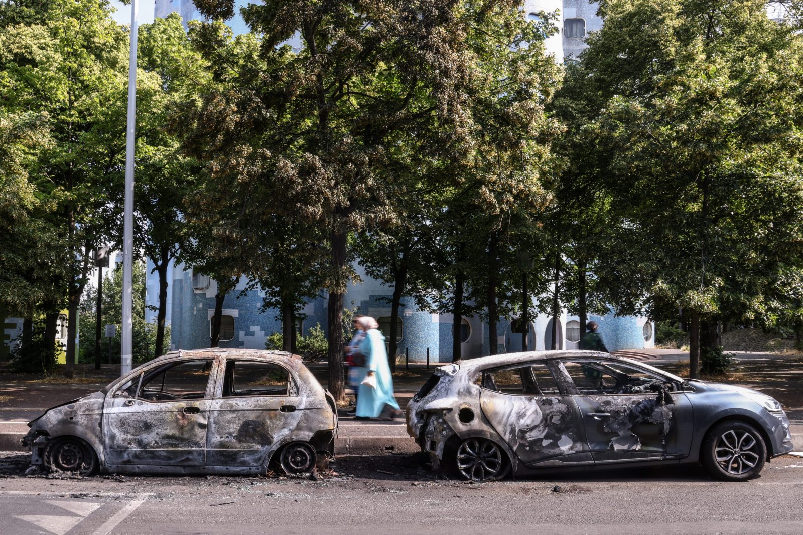 epa10715187 People walk past burnt out car on avenue Pablo Picasso following a night of civil unrest, in Nanterre, near Paris, France, 28 June 2023. The violence broke out after police fatally shot a 17-year-old during a traffic stop in Nanterre. According to the French interior minister, 31 people were arrested with 2,000 officers being deployed to prevent further violence.  EPA/Mohammed Badra