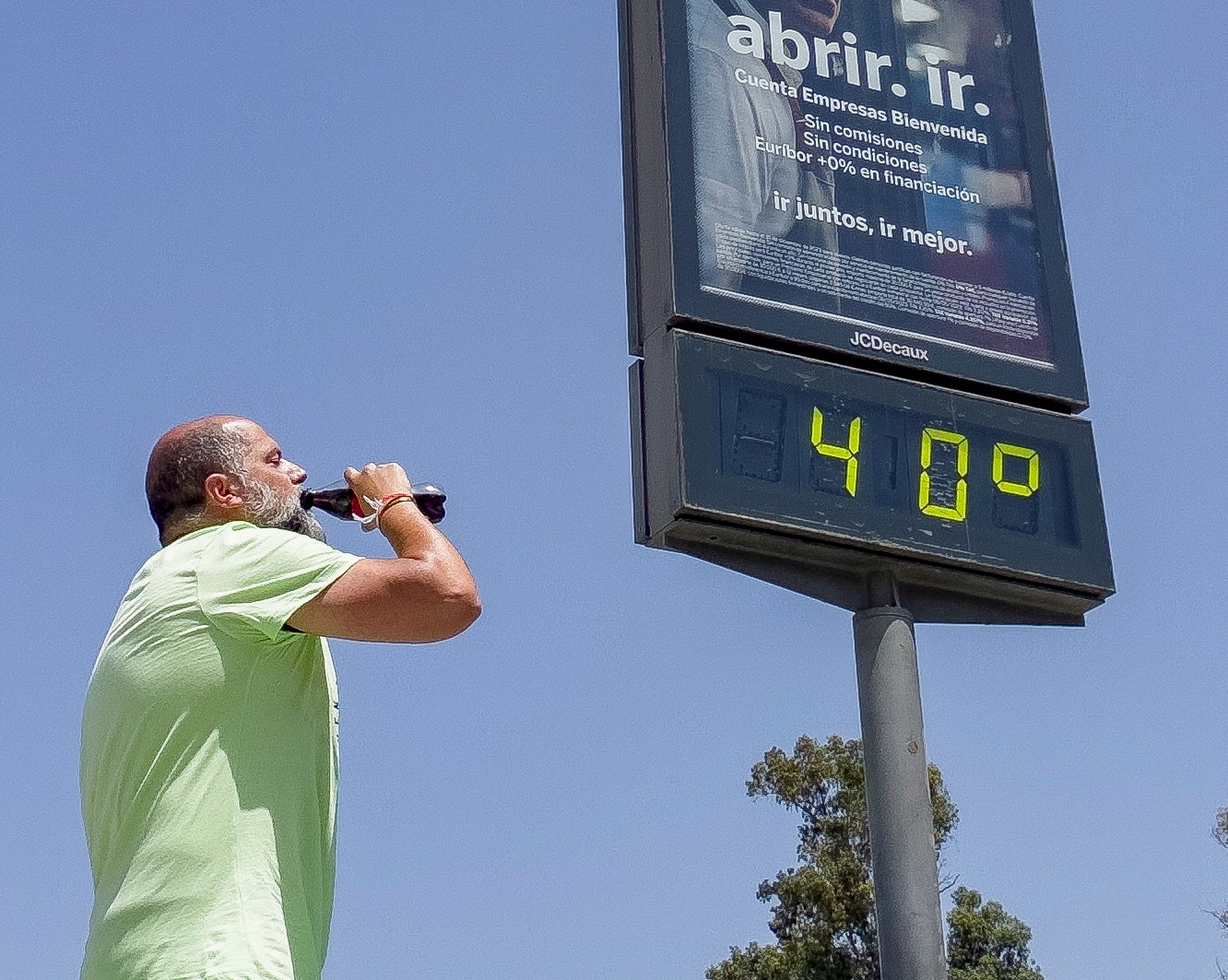 epa10710663 A man drinks next to a street thermometer displaying the temperature in Seville, Spain, 25 June 2023. The current anticyclonic situation in Spain has led to the first heat wave of the summer, which will last until 28 June and will be more pronounced in the southwest of the peninsula, where temperatures can even reach 45 degrees Celsius at its peak on 26 June.  EPA/DAVID ARJONA
