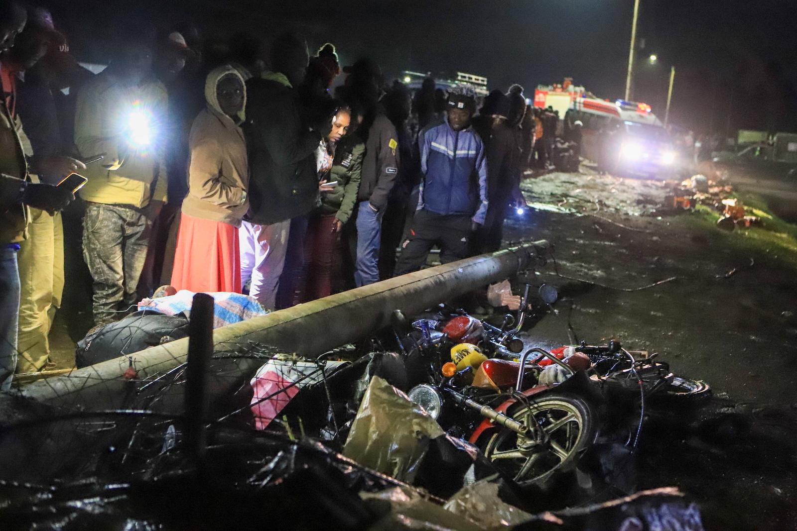 epa10720199 People mill around and search through the aftermath of a traffic accident in Londiani Junction area along the Kericho-Nakuru highway in Kericho County, Kenya's Rift Valley region, Kenya, 01 July 2023. According to a statement from Regional police commander Tom Odera, at least 48 people have been confirmed dead in the road accident, during which a truck carrying a shipping container rammed into several other vehicles and market traders along the Nakuru-Kericho highway.  EPA/STR