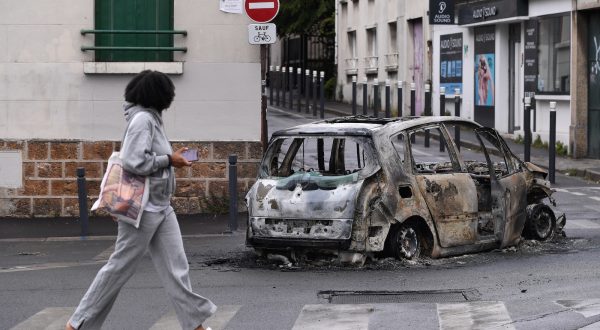 epa10720367 A person walks near the remains of a burnt out car following a night of looting and rioting in Montreuil, near Paris, France, 01 July 2023. Violence broke out across France over the fatal shooting of a 17-year-old teenager by a police officer during a traffic stop in Nanterre on 27 June.  EPA/JULIEN MATTIA