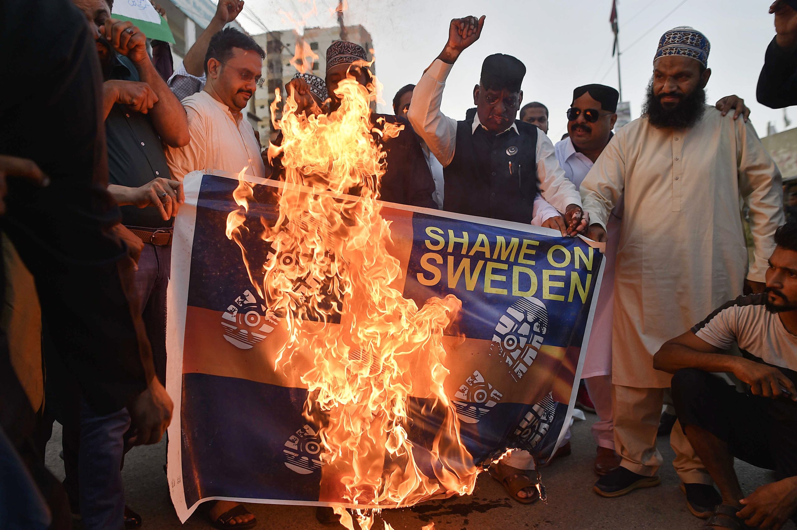 epa10722737 Demonstrators burn a mock Swedish flag as they attend a protest against the burning of a copy of the Koran in Sweden, in Karachi, Pakistan, 02 July 2023. Muslim activists staged protests across Pakistan against Sweden for allowing an Iraqi man to burn a copy of the Koran outside of a mosque in Stockholm.  EPA/SHAHZAIB AKBER
