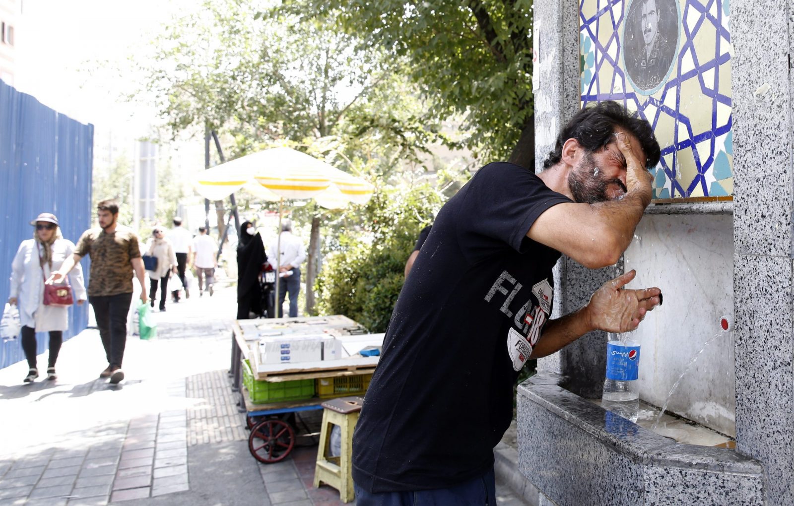 epa10727361 An Iranian man splashes water into his face at a public water well to cool off during a hot and sunny day in Tehran, Iran, 05 July 2023. Iran is facing a heat wave weather with temperatures above 35 degrees Celsius and forcasters'predictions of up to 40 degrees and more in the upcoming week.  EPA/ABEDIN ATEHRKENAREH