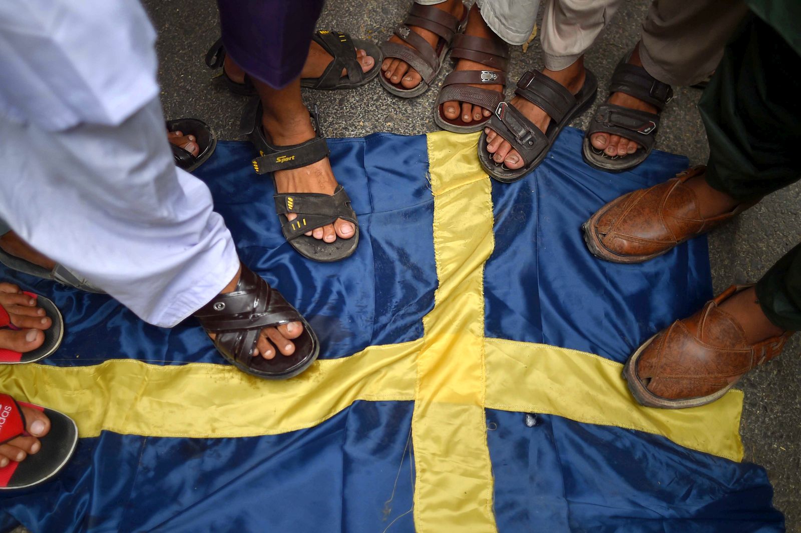 epa10732665 Demonstrators step on a mock Swedish flag during a protest against the burning of a copy of the Muslim holy book in Sweden, in Karachi, Pakistan, 07 July 2023. Pakistan's prime minister called for nationwide protests on 07 July against a recent desecration of the Koran, the holy book of Islam, in Sweden. An Iraqi refugee living in Sweden set fire to a copy of the Koran during a protest in front of a mosque in Stockholm on 28 June 2023. The act drew widespread outrage and condemnation from several countries, including Pakistan, Turkey, Saudi Arabia, Jordan, Palestine, Morocco, Iran, Iraq, and the European Union.  EPA/SHAHZAIB AKBER