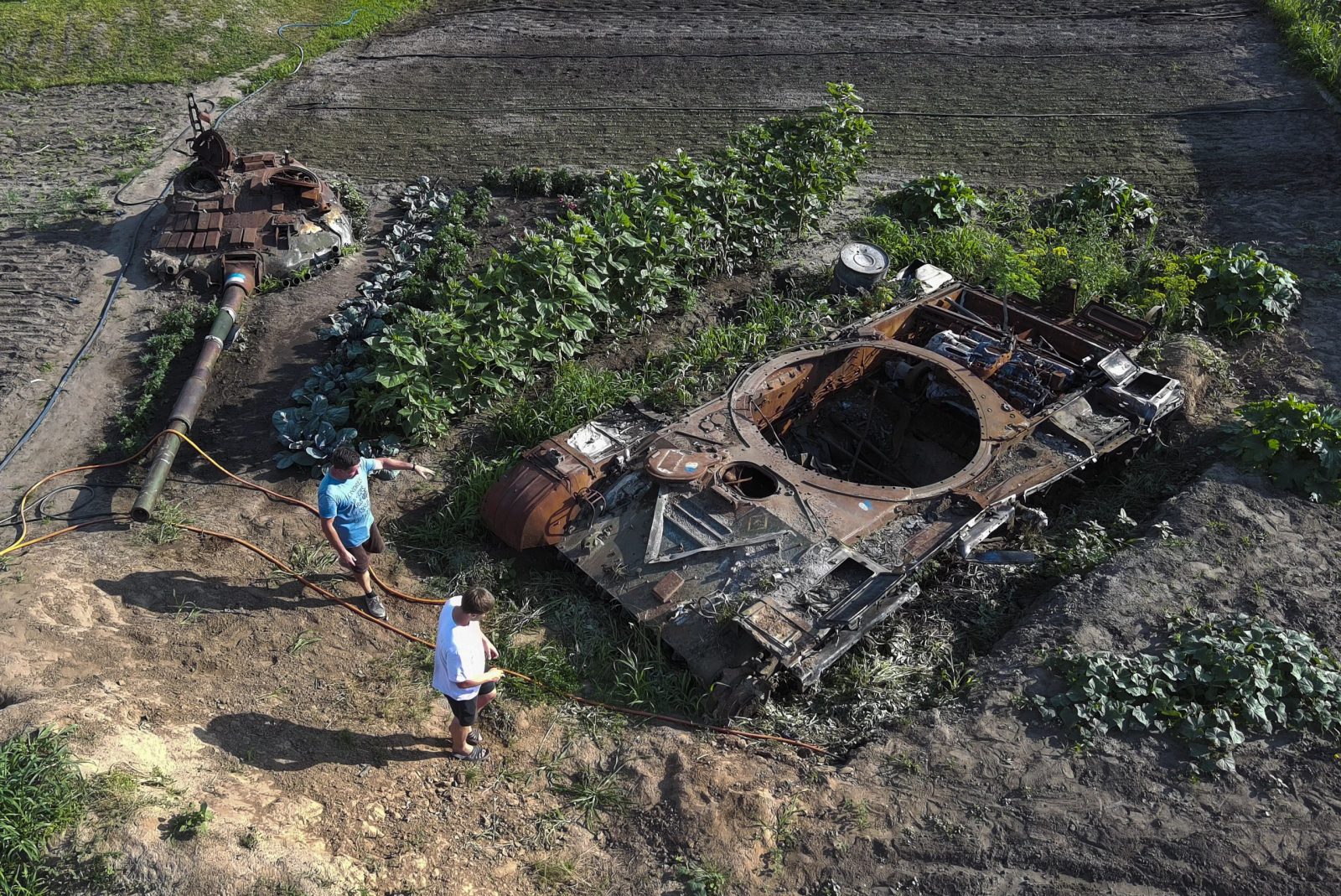 epa10734043 An aerial photo taken with a drone shows local men looking at the remains of a Russian tank in the middle of a garden at the village of Velyka Dymerka, Kyiv region, Ukraine, 05 July 2023 (issued 08 July 2023). Valeriy and Yulia Semynog, together with their three children, left their home when Russian troops arrived at Velyka Dymerka in March 2022. The family returned to their village only after Russian troops were pushed out from the Kyiv region in April 2022. They found their home destroyed along with the wreckage of a Russian tank in the garden. The locals planted flowers and vegetables between and around the wreckage of the tank. Velyka Dymerka as well as other towns and villages in the northern part of the Kyiv region, had become battlefields, heavily shelled, causing death and damage when Russian troops tried to reach the Ukrainian capital of Kyiv in February and March 2022.The war in Ukraine, marks on 08 July its 500th day.  According to the UN more than 9000 civilians have been killed since the war started.  EPA/SERGEY DOLZHENKO