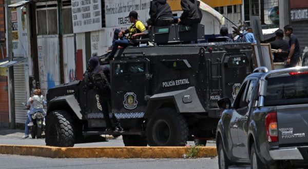 epa10738695 Protesters hang on to a hijacked police armored vehicle as they clash with police during a protest to demand the release of two detained transporters, in Chilpancingo, Guerrero state, Mexico, 10 July 2023. Protesters held captive a dozen state police officers and National Guard agents, and seized a police armored truck during clashes in the city of Chilpancingo.  EPA/JOSE LUIS DE LA CRUZ
