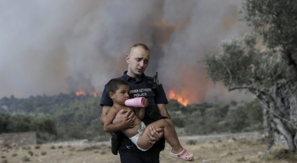 epa10753376 A Police officer Pavlos Terzoglou (26) carries a child as he and his colleagues forcibly evacuate a farmers’  family that refused to leave their property during a wildfire near the village of Palaiokoundouro, in Dervenochoria, northwest of Attica region, Greece, 18 July 2023. There are still active fires in Dervenochoria, in spite of the intervention of water-bombing aircraft according to government sources. A message was sent to people in Attica and the wider area around Dervenochoria via the emergency number 112, instructing them to stay indoors and close their doors and windows due to the ongoing wildfire.  EPA/KOSTAS TSIRONIS