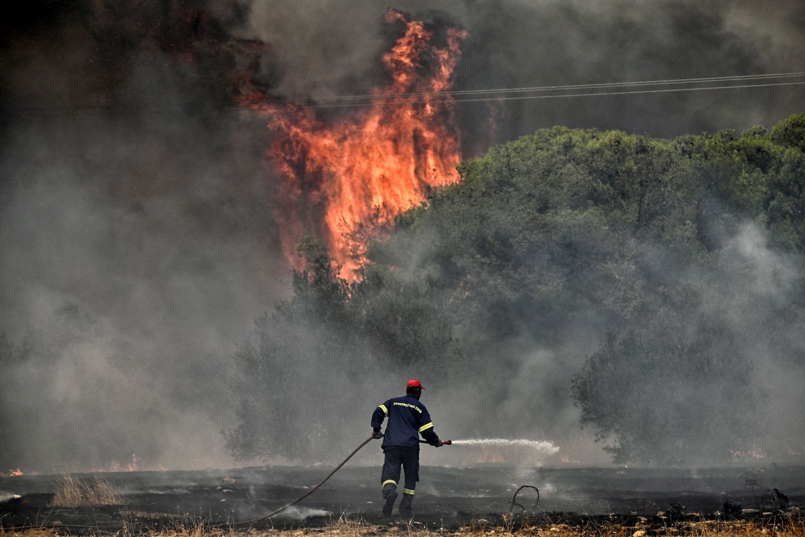 epa10753862 A firefighter operates during a wildfire at Aghios Charalambos area in Loutraki, Corinth, Greece, 18 July 2023. The Fire Brigade recommended the precautionary evacuation of the settlements Aghios Charalambos and Panorama in Loutraki. The fire front was burning over the Kallithea location and moving south-southeast above the Athens-Corinth national highway.  EPA/VASILIS PSOMAS