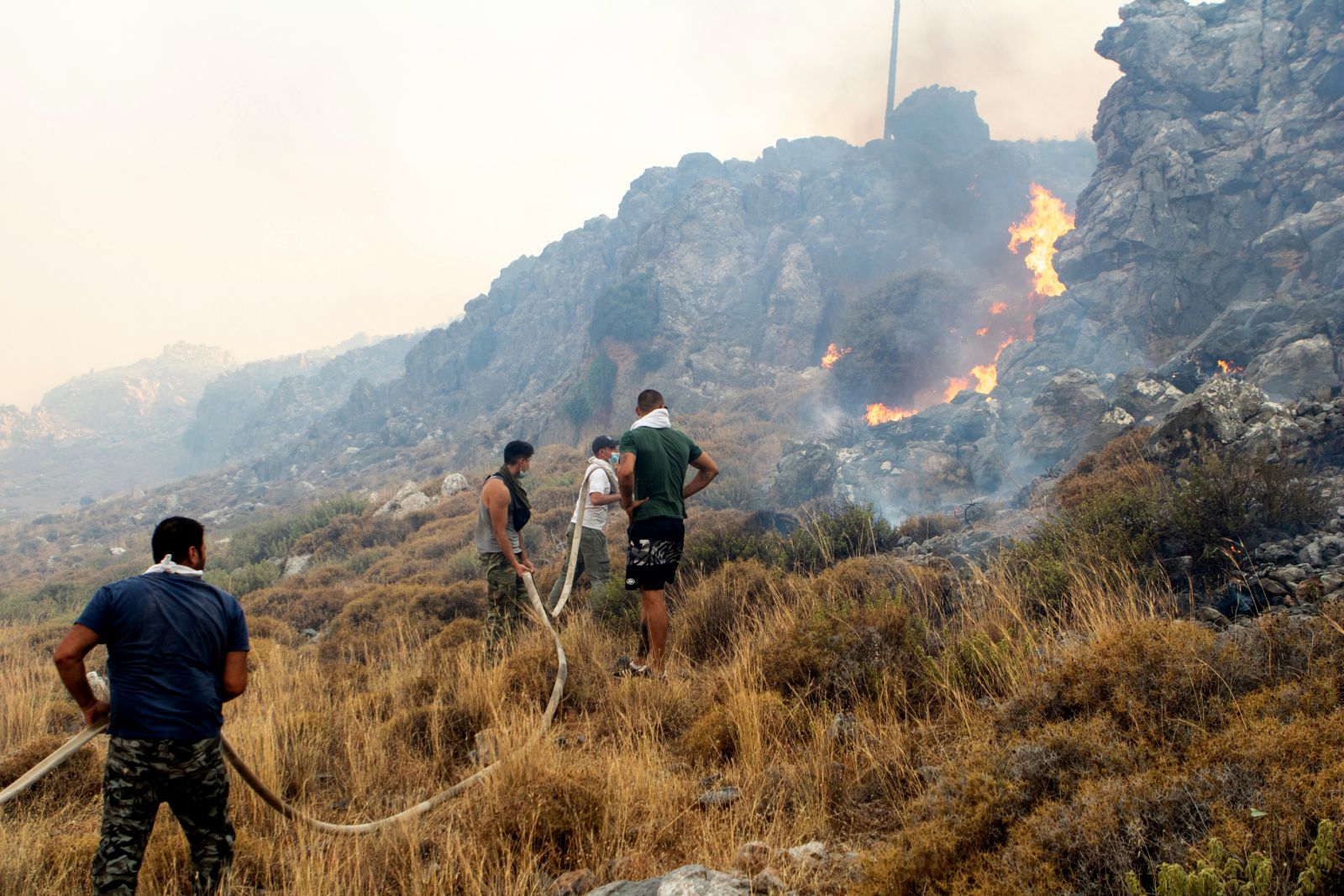epa10762697 Volunteers try to put out a wildfire  in Kiotari village, on Rhodes island, Greece 22 July 2023. Although the Fire Department had managed to put out several rekindled blazes on the island over the last few days, the wildfire near the village of Laerma in the island's north keeps expanding and moving eastwards to the Gadoura dam, while residents in the villages of Lardos and Pilonas were told to evacuated their homes on the day, via the emergency number 112. Some 173 firefighters with 35 fire engines and 10 ground teams are battling the blaze, assisted by 3 water bombers and 2 helicopters. Another 31 firefighters with 4 fire engines and 3 ground teams were also expected to arrive from Slovakia. Local authority water tanks are also helping out.  EPA/DAMIANIDIS LEFTERIS