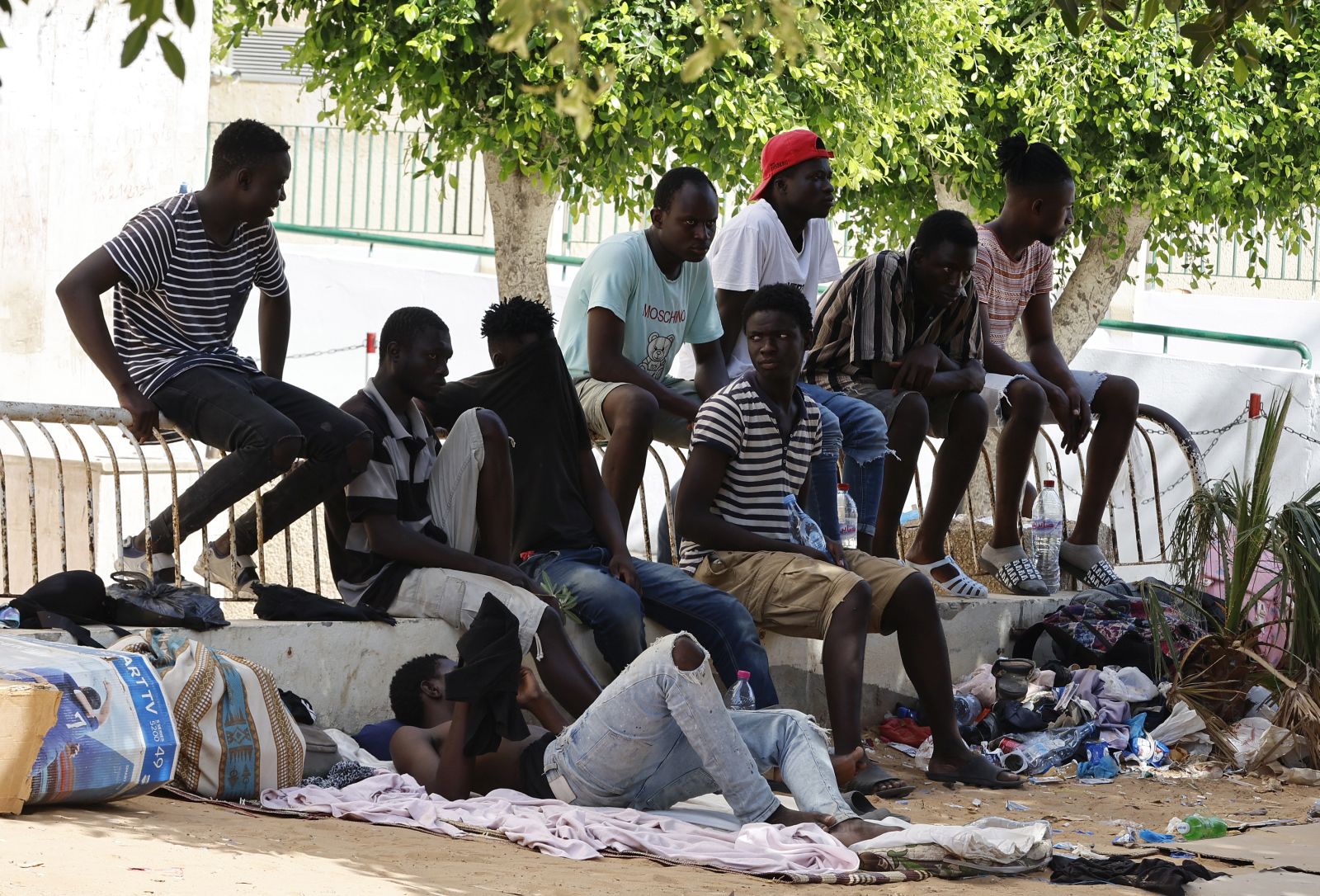 epa10760599 Sub-Saharan African migrants gather in a public garden in Sfax, in the south of Tunis, Tunisia, 21 July 2023. According to the Red Crescent, in Sfax, the second most important city in Tunisia, almost 1.500 Sub-Saharan African migrants, including children, try to find the shadow and water to survive in a public garden for two weeks. Most of them entered Tunisia in an unauthorized way and come from Sudan, Nigeria, Liberia, Mali, Burkina Faso and Guinea. According to the nongovernmental group Tunisian Forum for Economic and Social Rights (FTDES), between January and May 2023, Tunisian authorities arrested over 3,500 migrants for 'irregular stay' and intercepted over 23,000 people attempting irregular departures from Tunisia.  EPA/MOHAMED MESSARA