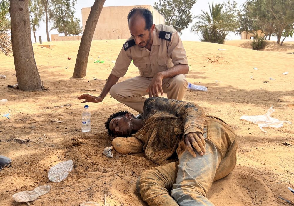 epa10777776 A Libyan border guard provides water to a Sub-Saharan African migrant, who reportedly have been abandoned by Tunisian authorities, upon his arrival in an uninhabited area on the Libya-Tunisia border near Al-Assah, 160 km west of Tripoli, Libya, 30 July 2023. Libyan border guards found more than 100 people, women, children and families, stranded in scorching summer temperatures and without water. According to the Red Crescent, Tunisian security forces have moved hundreds of migrants into the arid zone since June 2023.  EPA/STR