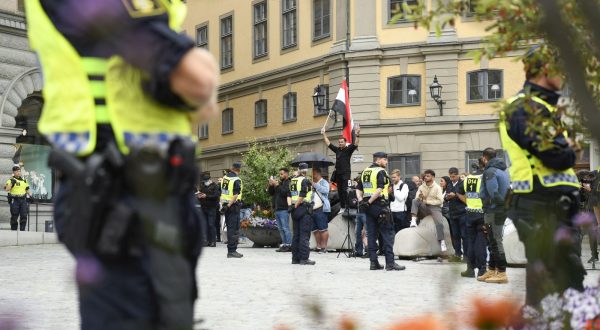 epa10778714 Police stand guard as a man (not in picture) prepares to  burn a copy of the Koran in protest, during a demonstration at Mynttorget in Stockholm, Sweden, 31 July 2023. Various Muslim organizations have condemned such actions holding protests against Sweden for allowing anti-Islam activists to desecrate and burn copies of the Muslim holy book of the Koran.  EPA/OSCAR OLSSON  SWEDEN OUT