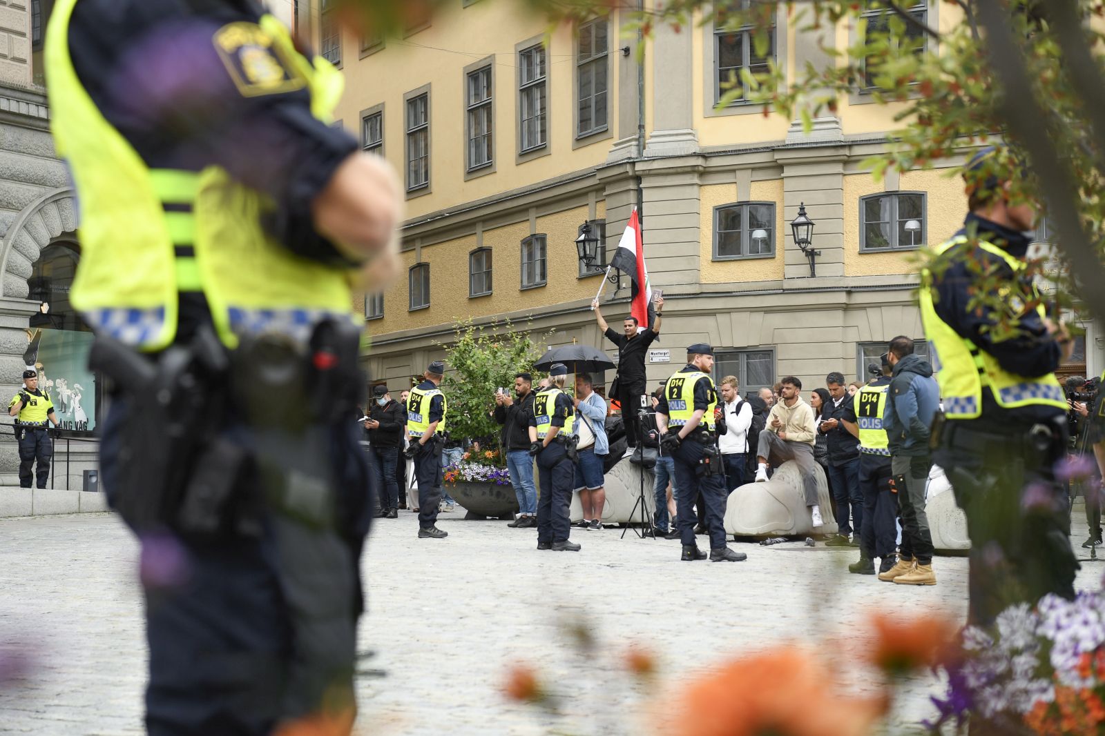 epa10778714 Police stand guard as a man (not in picture) prepares to  burn a copy of the Koran in protest, during a demonstration at Mynttorget in Stockholm, Sweden, 31 July 2023. Various Muslim organizations have condemned such actions holding protests against Sweden for allowing anti-Islam activists to desecrate and burn copies of the Muslim holy book of the Koran.  EPA/OSCAR OLSSON  SWEDEN OUT