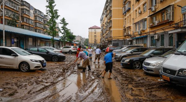 epa10779176 People clear a road from mud inside a residential compound in Mentougou District, west of Beijing, China, 01 August 2023. Heavy rains brought by Typhoon Doksuri caused floods in northern China and left two dead and thousands being evacuated as Beijing experienced its heaviest rainfall of the year.  EPA/MARK R. CRISTINO