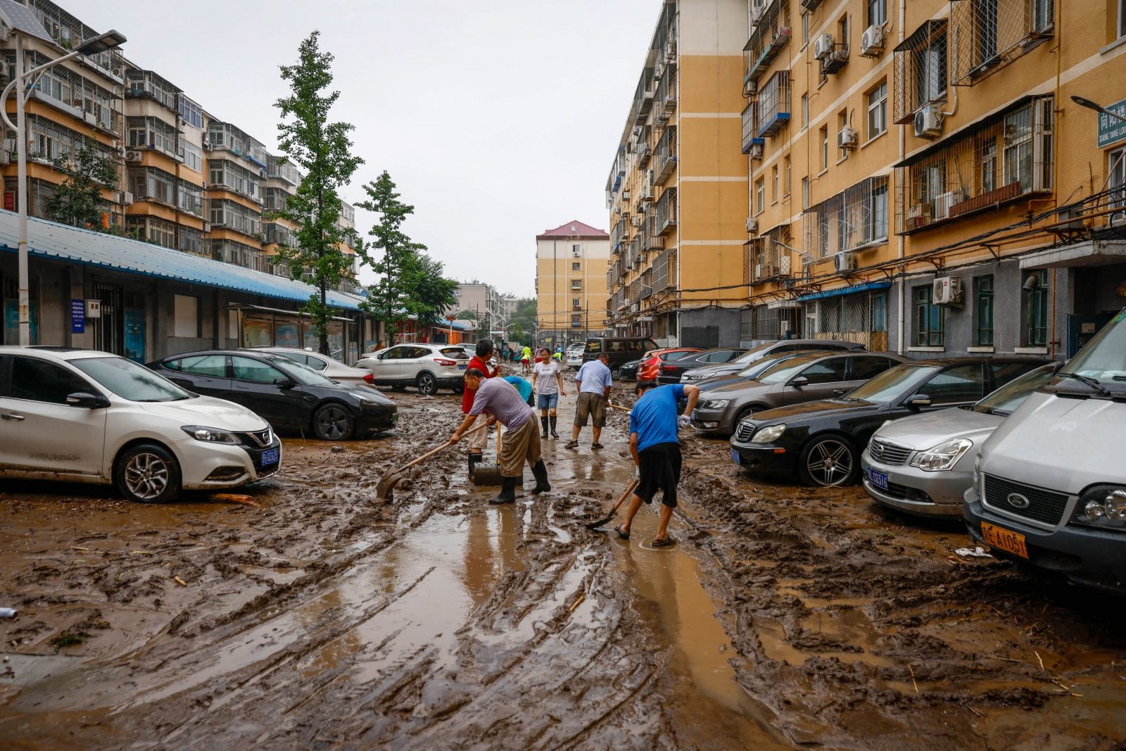 epa10779176 People clear a road from mud inside a residential compound in Mentougou District, west of Beijing, China, 01 August 2023. Heavy rains brought by Typhoon Doksuri caused floods in northern China and left two dead and thousands being evacuated as Beijing experienced its heaviest rainfall of the year.  EPA/MARK R. CRISTINO
