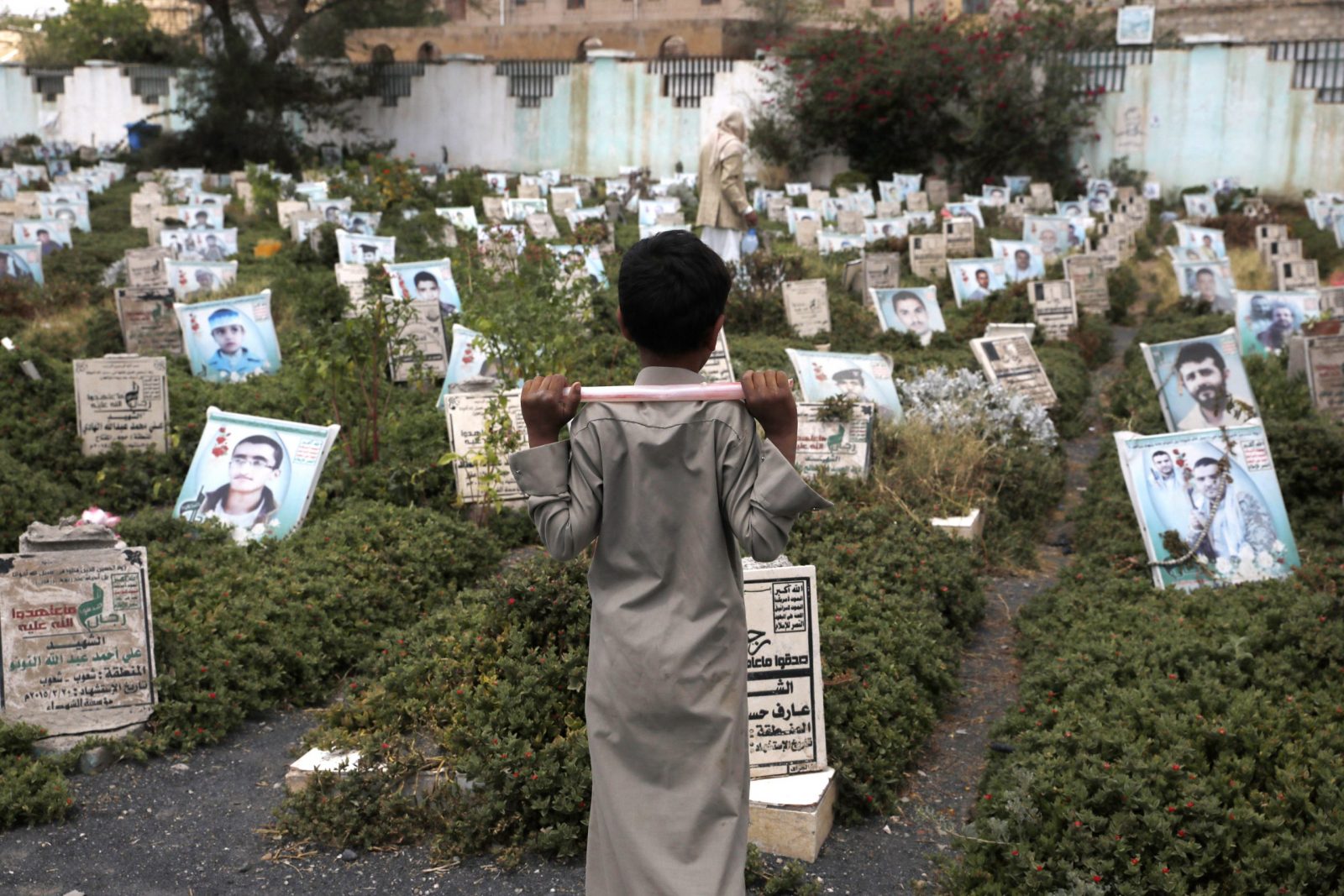epa10800228 A Yemeni child stands next to graves with portraits of children killed in Yemen's prolonged war, at a cemetery in Sana'a, Yemen, 14 August 2023. The Houthis movement has accused the Saudi-led coalition of killing over 8,000 children in Yemen since the war began in March 2015 when the coalition launched a military operation and an airstrike campaign against the Houthis who drove out the Saudi-backed Yemeni government from large parts of the Arab country, including the capital Sana'a.  EPA/YAHYA ARHAB