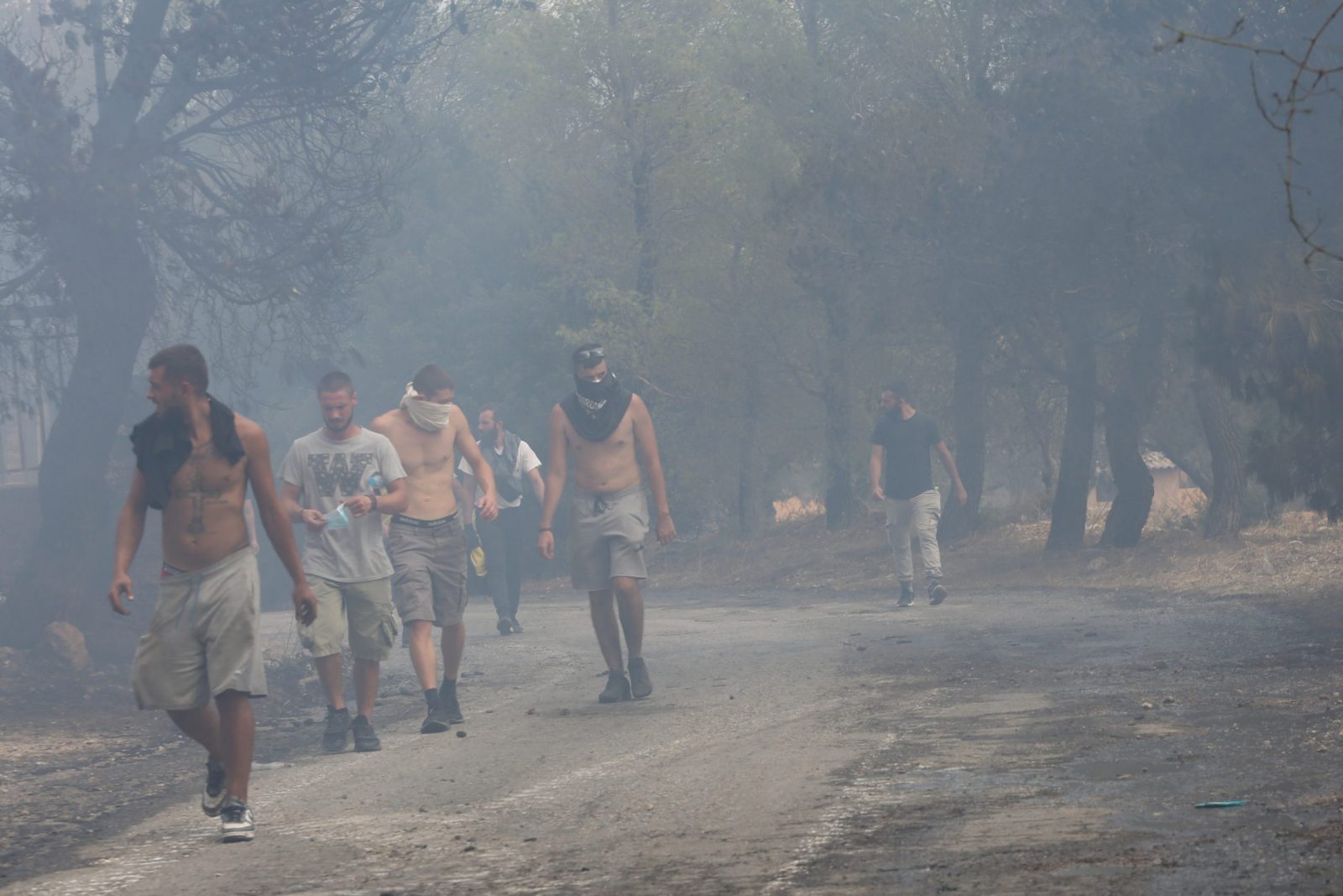 epa10816000 Residents walk through the smoke at Agia Paraskevi village near Acharnes, Attica, Greece, 23 August 2023. Fire Brigade forces continue to battle a series of fire fronts across the country as a total of 209 wildfires broke out.  EPA/ALEXANDROS BELTES