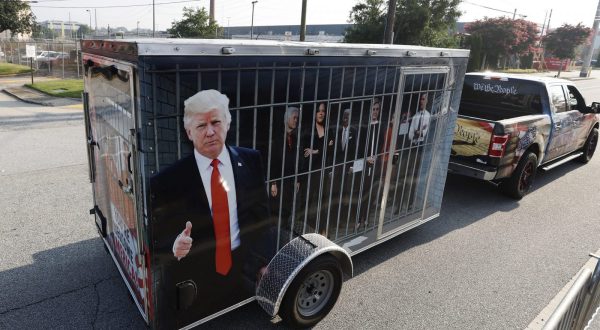 epa10817577 A supporter of former US President Donald Trump tows a makeshift jail cell containing depictions of Democratic leaders, outside the entrance of the Fulton County Jail, prior to the arrival of Trump to turn himself into authorities after a grand jury indictment against him and 18 co-defendants for 2020 election interference in Atlanta, Georgia, USA, 24 August 2023.  EPA/ERIK S. LESSER