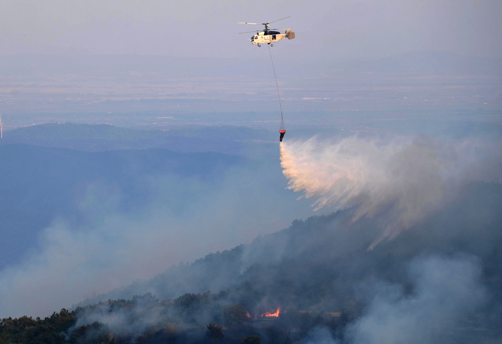 epa10823224 A firefighting helicopter drops water during efforts to put out wildfire in the area of Leptokarya, Evros, northern Greece, 26 August 2023 (issued 27 August 2023). According to the Fire Department, the main front of the Evros fire is located in the area of Leptokarya, while flare-ups occurred during the night in Dadia. Strong ground firefighting forces, along with volunteer firefighters and forces of the Armed Forces are participating in the operation in Evros, assisted by four aircraft and three helicopters.  EPA/DIMITRIS ALEXOUDIS