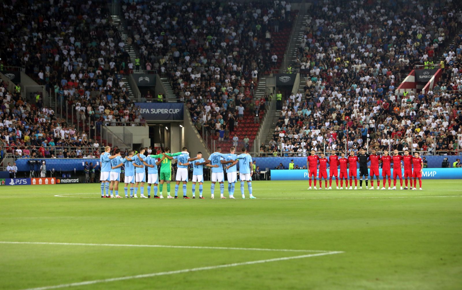 epa10803359 The players hold a minute of silence for a fan of AEK Athens who lost his life in a hooligan dispute, before the UEFA Super Cup soccer match between Manchester City and Sevilla FC at Karaiskakis Stadium in Piraeus, Greece, 16 August 2023.  EPA/PANAGIOTIS MOSCHANDREOU