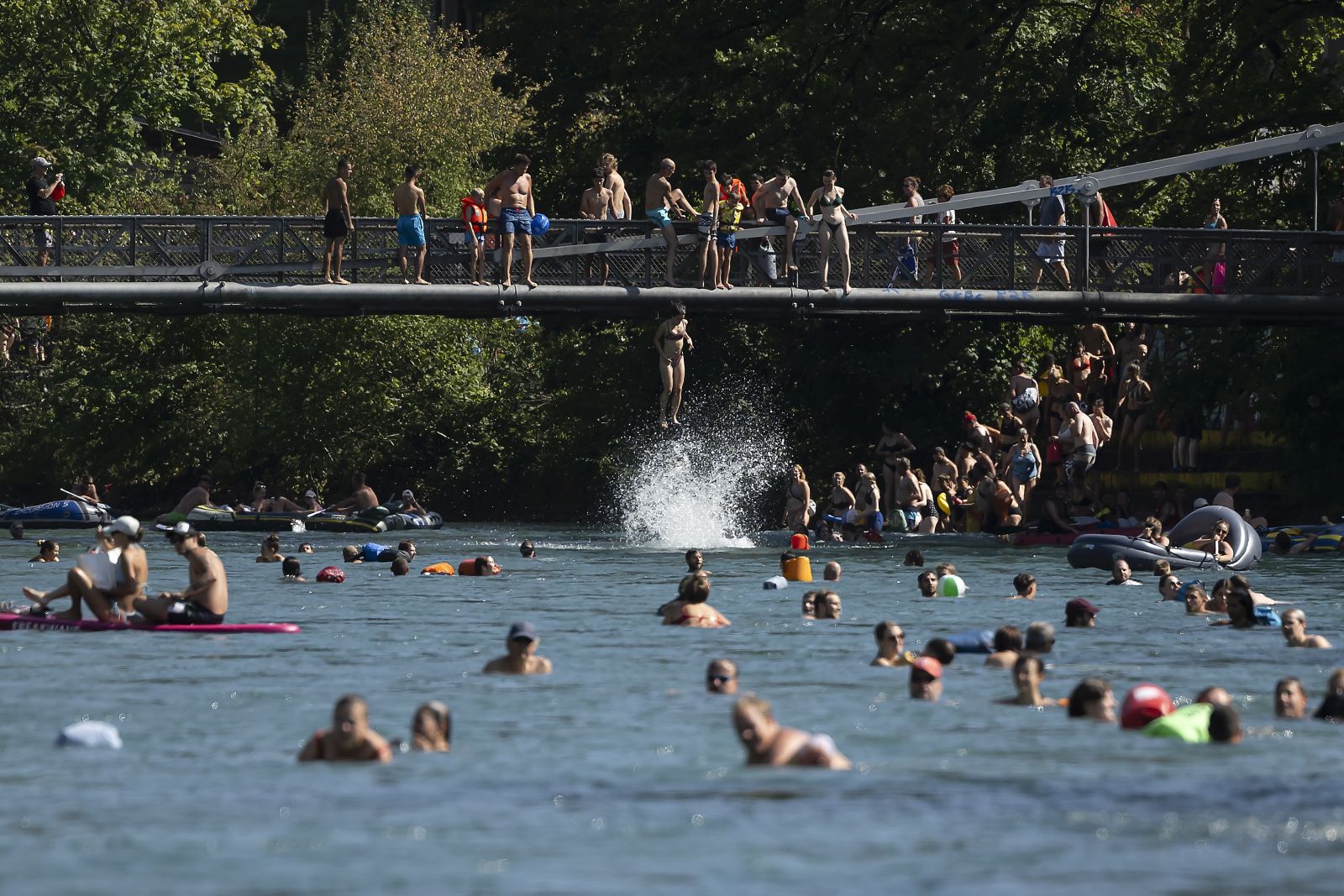 epa10810771 A woman jump from Schonausteg bridge in the Aare River during the sunny and warm weather in Bern, Switzerland, 20 August 2023. Many parts of Switzerland have been experiencing a period of extreme heat. A heat dome has been hovering over the country for an indefinite period since 18 August.  EPA/ANTHONY ANEX