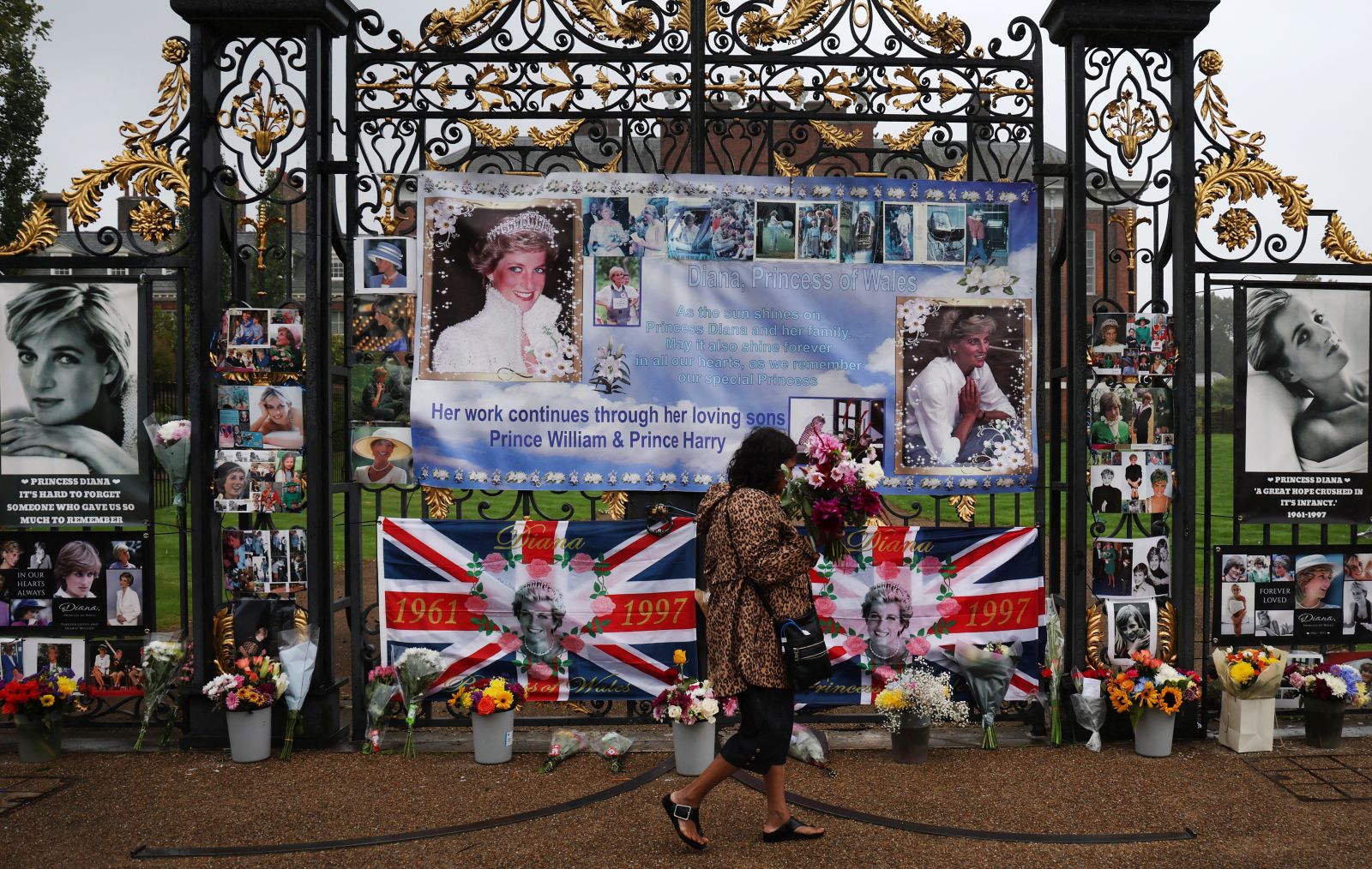 epa10831164 A royal well-wisher walks past tributes for Princess Diana at the gates of Kensington Palace, the former home of Britain’s Princess Diana in London, Britain, 31 August 2023. People gathered outside the palace to mark the 26th anniversary of death of Princess Diana who died in a car crash in Paris, France.  EPA/ANDY RAIN