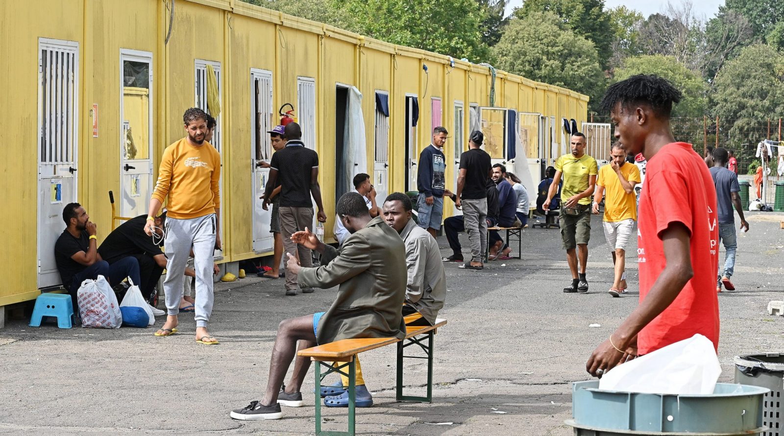 epa10871641 Migrants gather outside containers at the Red Cross reception centre in Via Tres, Turin, Italy, 20 September 2023. The center houses some 500 people in a compound and facilities which are meant for between 140 and 180 people in need. Italy saw an influx of thousands of migrants in the past weeks. According to Italy's Interior Ministry, nearly 126,000 immigrants and refugees have entered the country as of 2023, more than twice as many as during the same time period in 2022.  EPA/ALESSANDRO DI MARCO
