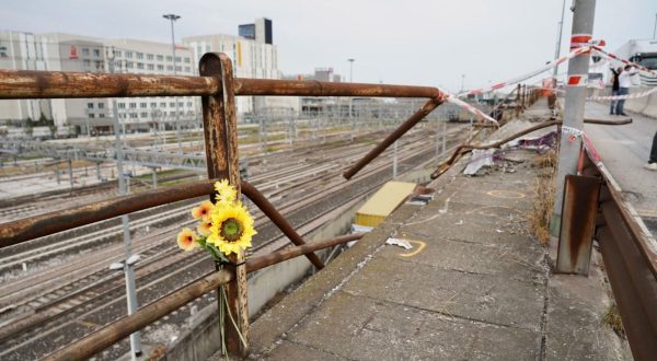 epa10899507 People placed flowers at the site on an overpass from where a bus crashed last night, claiming 21 lives, in Mestre, near Venice, Italy, 04 October 2023. The Venice prefect's department has confirmed that 21 people are dead after a bus plunged from an overpass above a railway line between the districts of Mestre and Marghera on late 03 October. The methane-powered bus burst into flames after falling over 10 meters from the overpass.  EPA/MARCO ALBERTINI