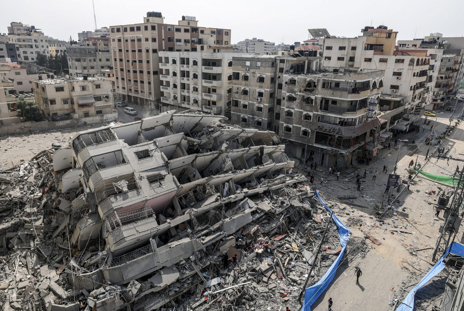 epa10907218 An aerial view shows people inspecting the destroyed Al-Aklouk Tower following Israeli air strikes, in Gaza City, 08 October 2023. The air strikes, in retaliation for the 07 October Hamas rocket attacks on Israel, have killed over 300 people in the Gaza Strip, with almost 2,000 wounded, according to Palestinian official sources.  EPA/MOHAMMED SABER