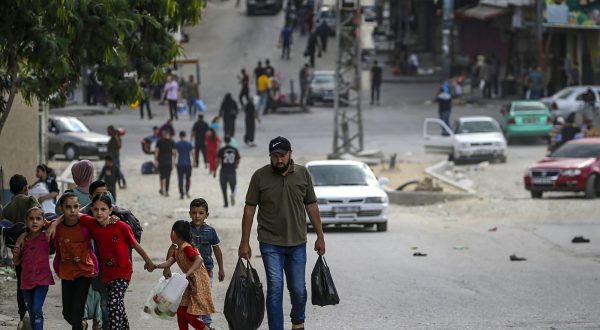 epa10922364 A Palestinian carrying food walks with his children in Al Shejaeiya neighbourhood, east of Gaza City, 16 October 2023. Israel has warned all citizens of the Gaza Strip to move to the south ahead of an expected invasion. More than 2,750 Palestinians and 1,400 Israelis have been killed according to the Israel Defense Forces (IDF) and Palestinian Health Ministry after Hamas militants launched an attack against Israel from the Gaza Strip on 07 October.  EPA/MOHAMMED SABER