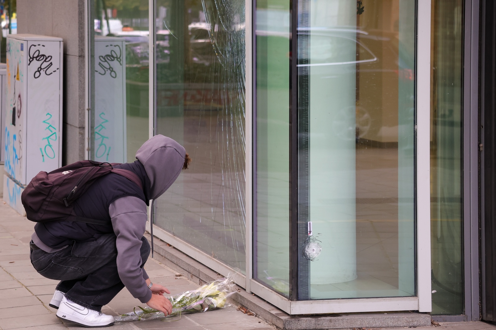epa10923205 Flowers are put in place at the bank branch, where two football supporters from Sweden were shotdead in a terror attack in Brussels, Belgium, 17 October 2023. A man, suspected of killing two Swedish football supporters on 16 October, was shot by the Police during an operation and has died, Belgian Police said. Following the incident, the Brussels Capital Region has increased its terror threat to level 4, the highest, the National Crisis Center announced.  EPA/OLIVIER MATTHYS