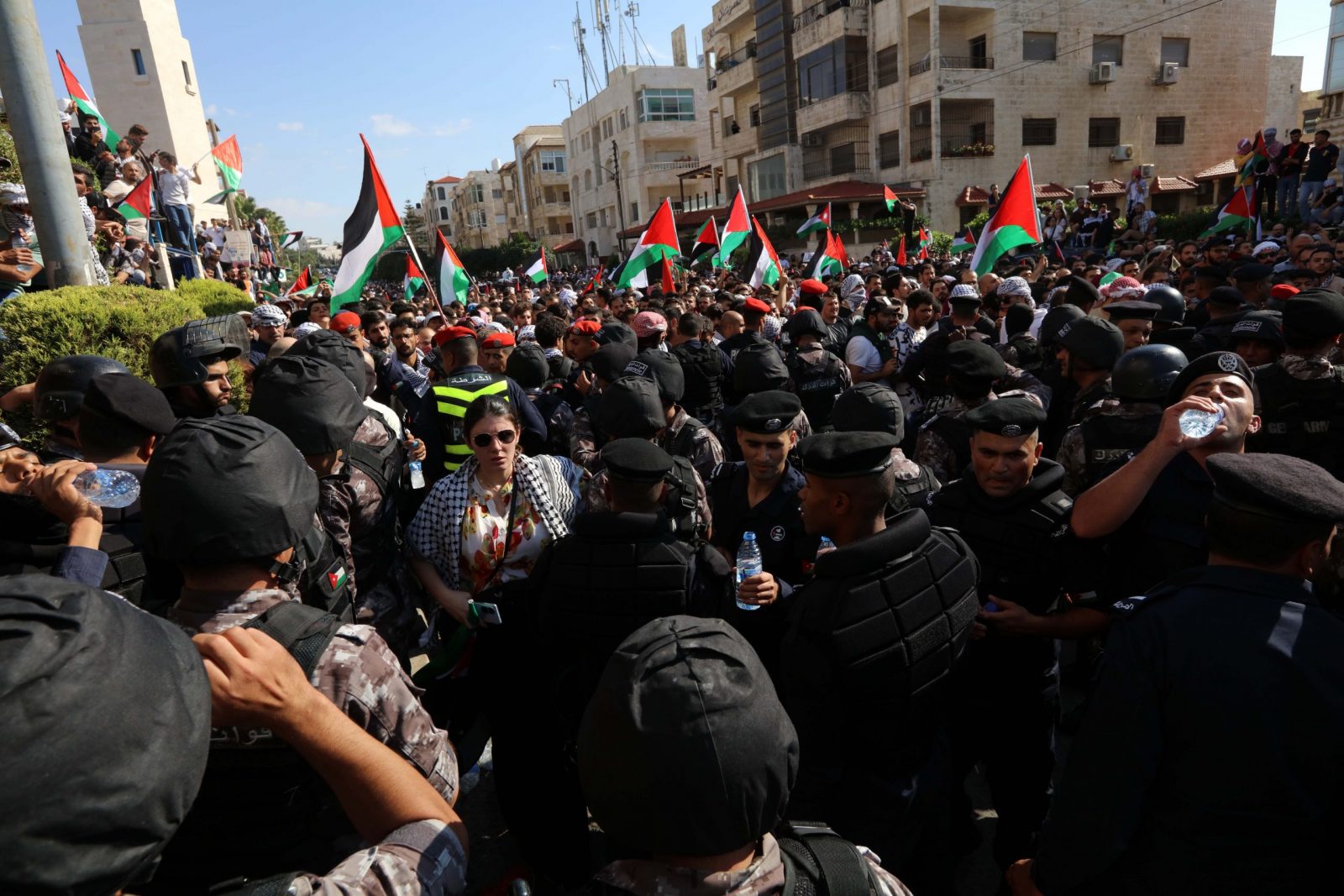 epa10925636 Members of the security forces stand guard in front of protesters holding Palestinian flags during a pro-Palestinian rally near the Israeli embassy following a strike on a hospital in the Gaza Strip, in Amman, Jordan, 18 October 2023. According to Palestinian authorities in Gaza hundreds of people have been killed in the explosion at a hospital in Gaza on 17 October. Israel has denied responsibility and said a Palestinian Islamic Jihad (PIJ) rocket misfire caused the blast.  EPA/MOHAMMAD ALI
