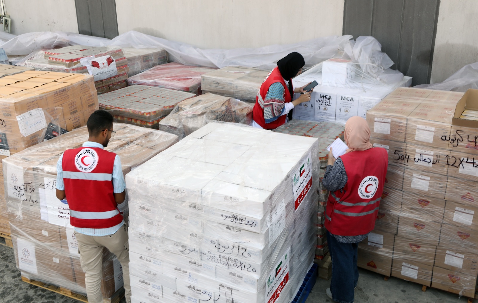 epa10944749 Egyptian Red Crescent Society employees handle humanitarian aid bound for Palestinians in the Gaza Strip, at a warehouse in Arish, Egypt, 28 October 2023. More than 7,000 Palestinians and at least 1,300 Israelis have been killed, according to the Israel Defense Forces (IDF) and the Palestinian health authority, since Hamas militants launched an attack against Israel from the Gaza Strip on 07 October, and the Israeli operations in Gaza and the West Bank which followed it.  EPA/KHALED ELFIQI