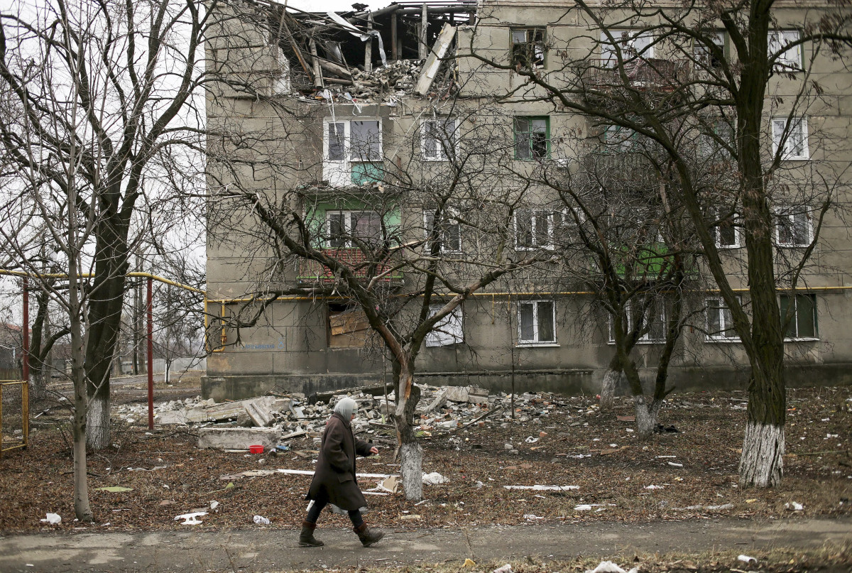 epa04642193 A local woman walks past a damaged with shelling building in Popasne village of Luhansk area, Ukraine, 28 February 2015. Ukraine is withdrawing heavy weapons from its front line in the east in order to test if a peace plan with separatist rebels can work, President Petro Poroshenko said 27 February 2015. The separatists say that they began the withdrawal days earlier. Both sides claim that observers from the Organization for Security and Co-operation (OSCE) are monitoring the withdrawal.  EPA/ANASTASIA VLASOVA