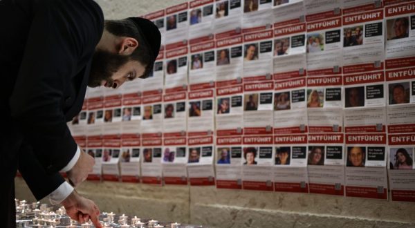 epa10956305 A participant lights a candle in front of kidnapped person's fliers at the Synagogue Muenstersche Strasse in Berlin, Germany, 03 November 2023. The Jewish Community Chabad Berlin held a candle-lighting ceremony for the hostages held by Hamas. At least 242 hostages are being held in Gaza according to the Israel Defense Forces (IDF) and the Palestinian health authority, since Hamas militants launched an attack against Israel from the Gaza Strip on 07 October 2023.  EPA/CLEMENS BILAN