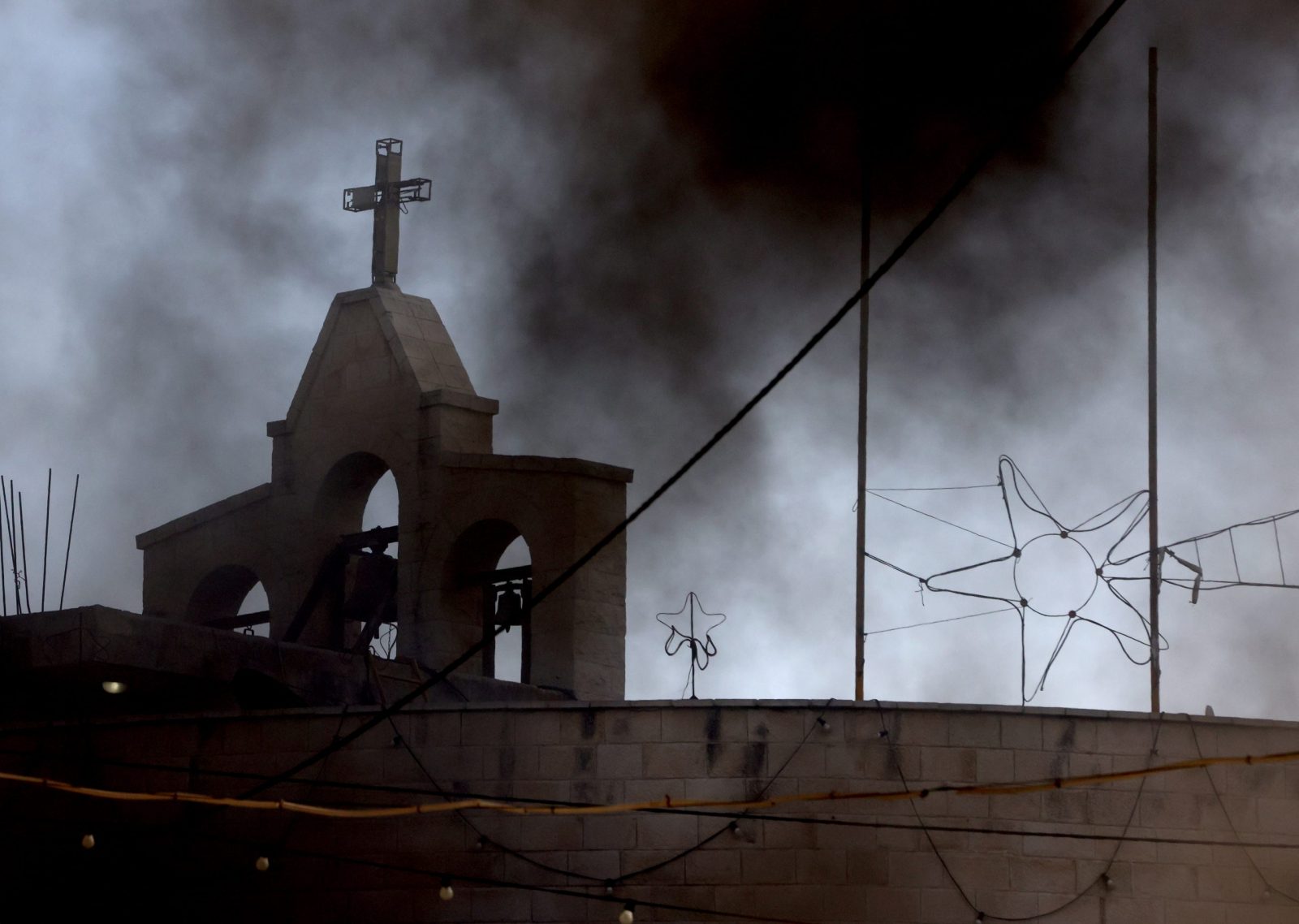 epaselect epa10966319 Black smoke rises over the Jenin church during clashes between Palestinians and Israeli troops following an Israeli raid at the Jenin refugee camp, in the West Bank city of Jenin, 09 November 2023. According to the Palestinian Health Ministry, at least nine Palestinians were killed and around 15 others were injured during heavy clashes with Israeli troops. Since 07 October 2023, more than 160 Palestinians have been killed, while over 2,000 have sustained injuries in the West Bank.  EPA/ALAA BADARNEH