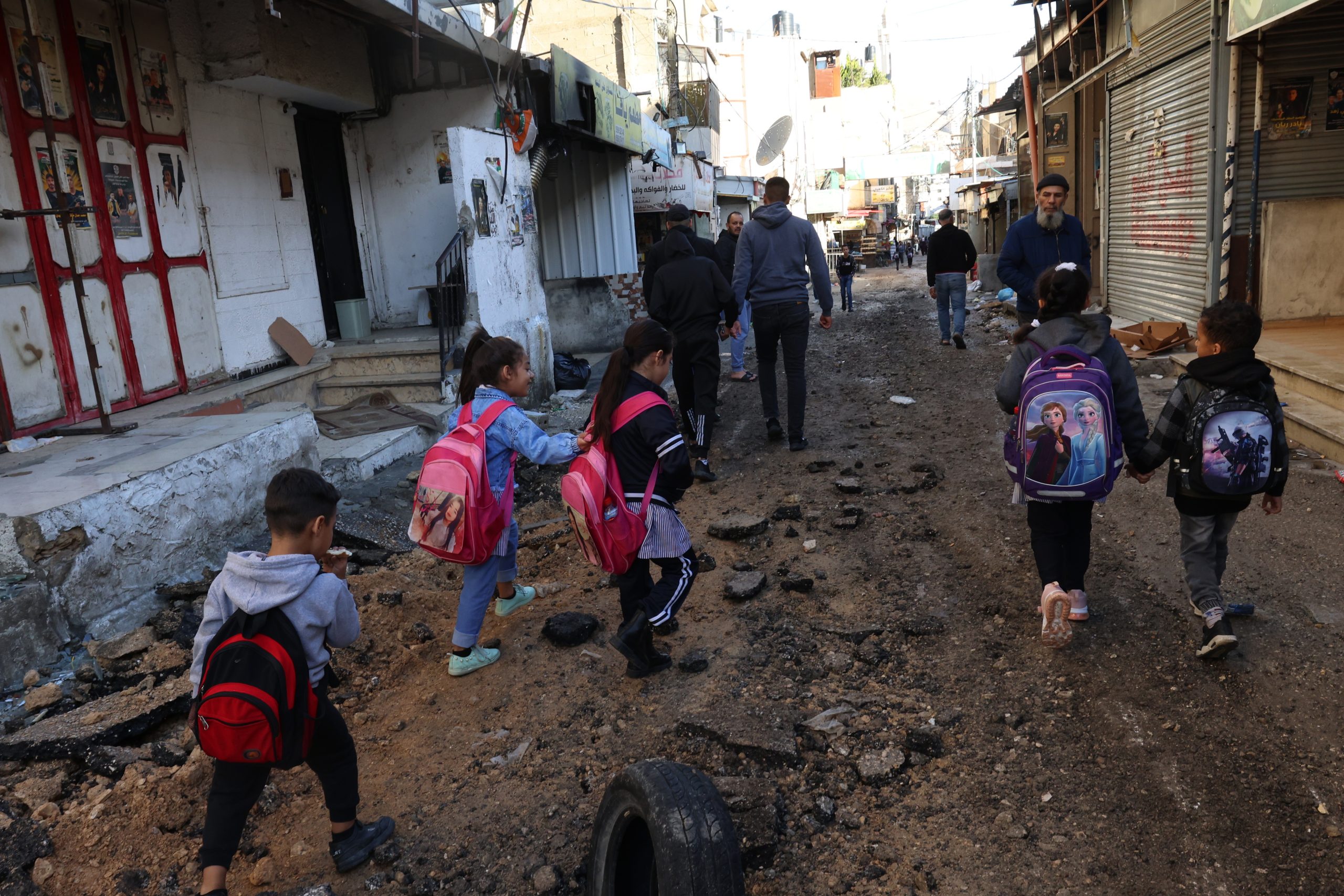 epa10987619 Palestinian school children move along a damaged street  after an Isareli army operation at Balta refugee camp, near Nablus, West Bank, 21  November 2023. According to the Palestinian Red Crescent, nine people were injured in the operation. More than 12,000 Palestinians and at least 1,200 Israelis have been killed, according to the Israel Defense Forces (IDF) and the Palestinian health authority, since Hamas militants launched an attack against Israel from the Gaza Strip on 07 October, and the Israeli operations in Gaza and the West Bank which followed it.  EPA/ALAA BADARNEH