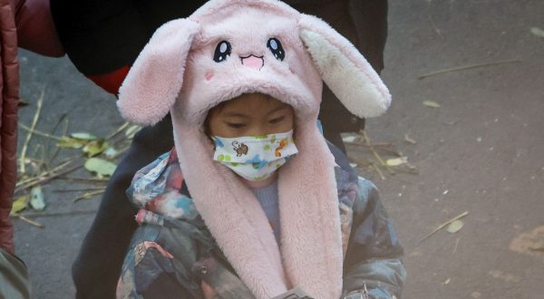 epa10990531 A child wears a face mask after dismissal from a school in Beijing, China, 23 November 2023. The World Health Organization (WHO) made an official request to China for detailed information following an increase of respiratory diseases and reported clusters of pneumonia in children in northern China.  EPA/MARK R. CRISTINO