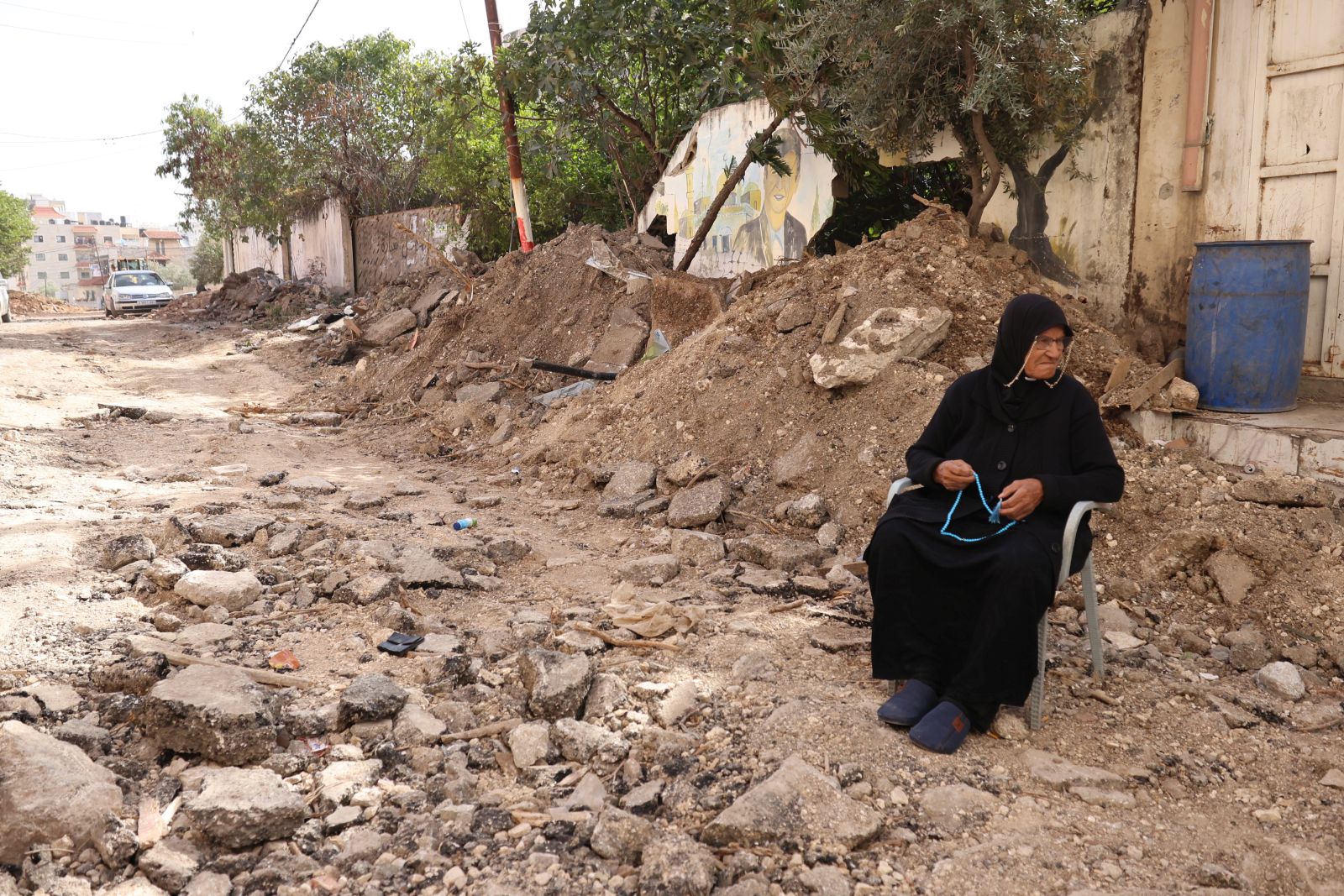 epa10996009 People woman sits amidst the rubble in a street after an Israeli raid on the Jenin refugee camp in the West Bank city of Jenin, 26 November 2023. According to the Palestinian Health Ministry, five Palestinians were killed and 15 others injured in the overnight Israeli raid on the Jenin camp and ensuing clashes.  EPA/ALAA BADARNEH