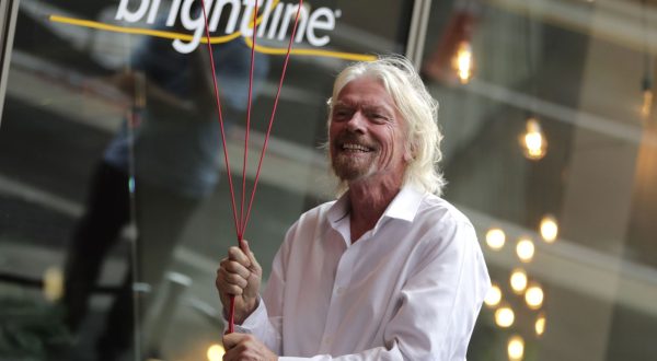 FILE - Richard Branson, of Virgin Group, prepares to unfurl a banner during a naming ceremony for the Brightline train station, to be renamed as Virgin MiamiCentral in Miami on April 4, 2019. A British judge ruled in favor of Richard Branson's Virgin group on Thursday Oct. 12, 2023 in its lawsuit against a U.S. train company that terminated a licensing agreement and claimed the Virgin brand was no longer one of “high repute.” (AP Photo/Lynne Sladky, File)