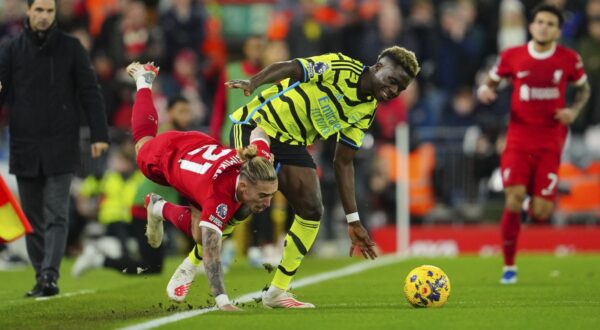 Liverpool's Kostas Tsimikas, left, is fouled by Arsenal's Bukayo Saka during the English Premier League soccer match between Liverpool and Arsenal at Anfield stadium in Liverpool, England, Saturday, Dec. 23, 2023. (AP Photo/Jon Super)