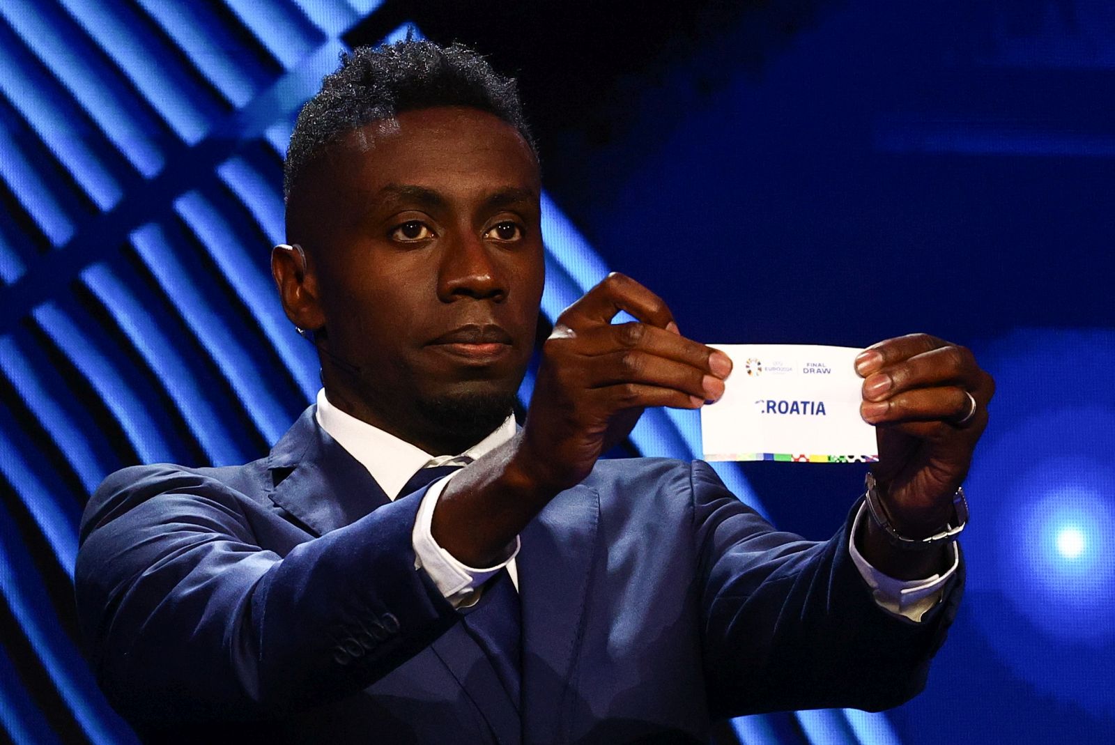 epa11007817 Former French football player Blaise Matuidi holds a ticket of Croatia during the UEFA EURO 2024 final tournament draw at the Elbphilharmonie in Hamburg, Germany, 02 December 2023. The UEFA EURO 2024 will take place in Germany from 14 June to 14 July.  EPA/FILIP SINGER